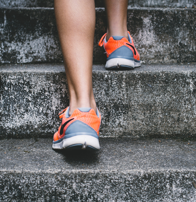 Rear view of runner's feet in trainers going up stone steps