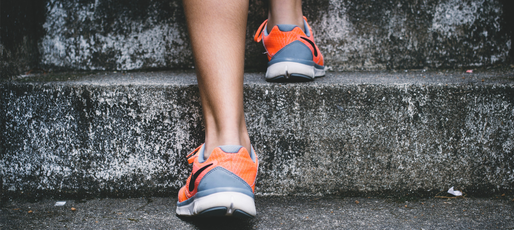 Rear view of runner's feet in trainers going up stone steps