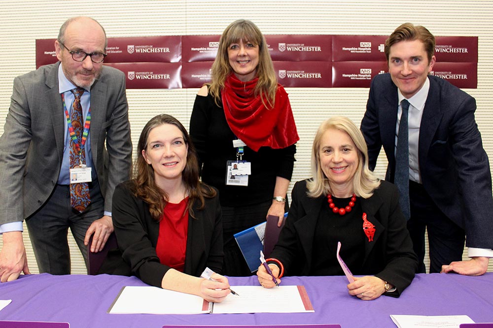 Group of five people around table at signing ceremony