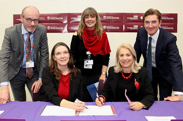 Signing of agreement with five people around a table