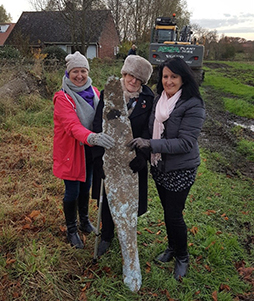 Three women in field holding part of a plane propeller
