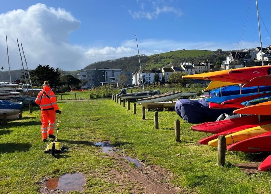 Man dragging small yellow trailer through boatyard