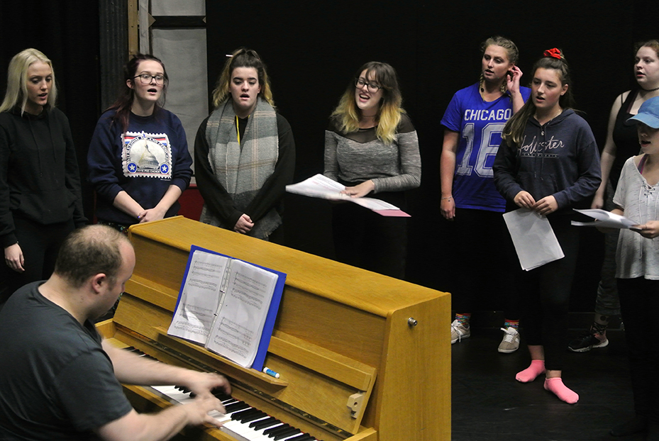 Group of people singing around a piano