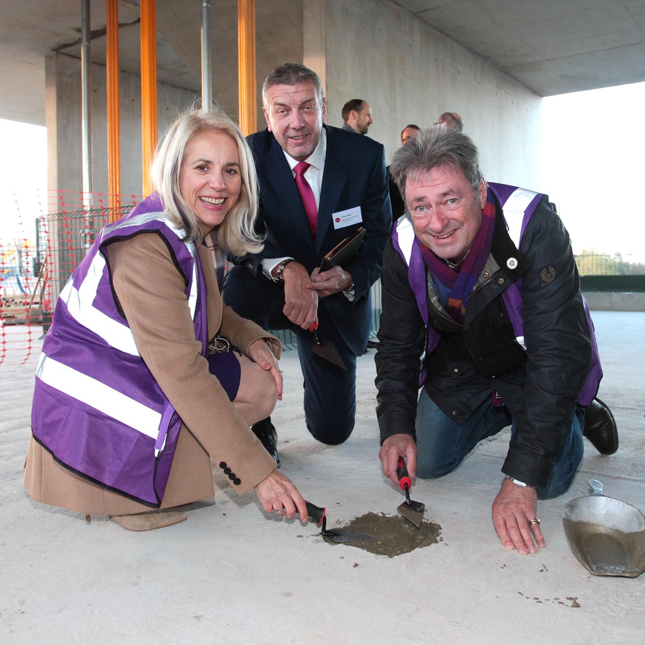 Three people outside on the terrace of a building under construction