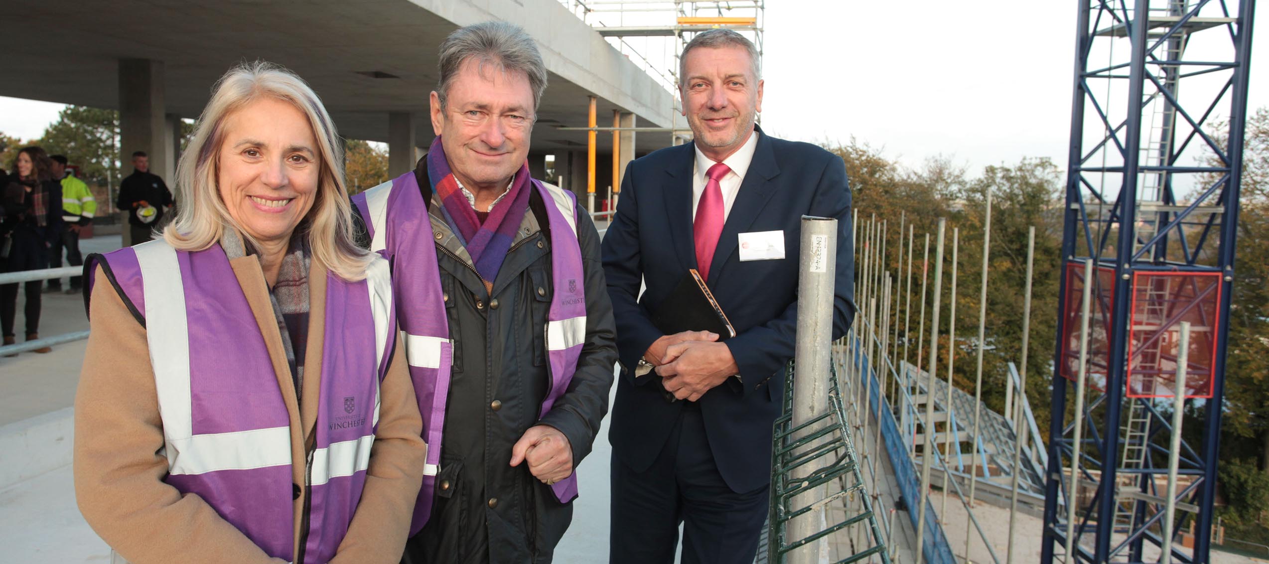 Three people outside on the terrace of a building under construction