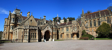 Exterior of large Victorian stone mansion against a bright blue sky