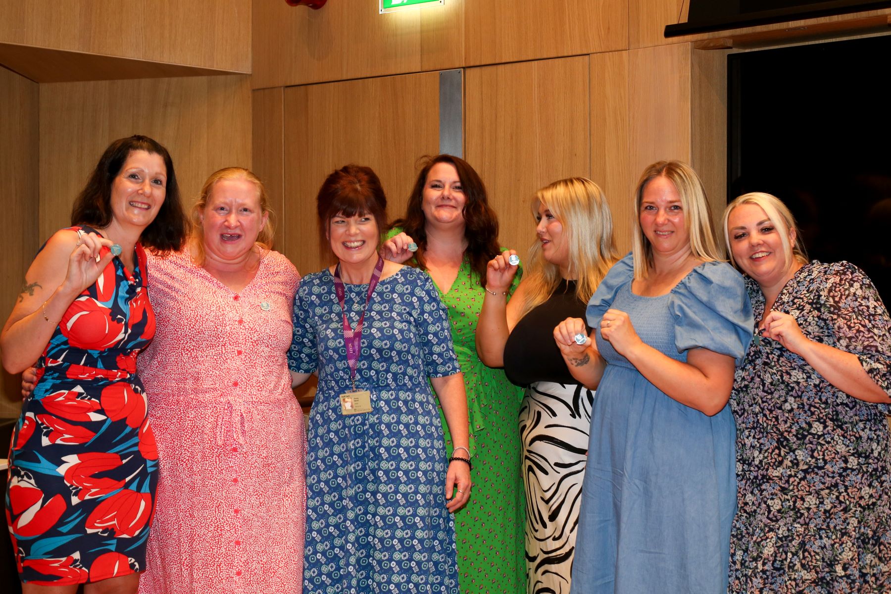 women stood together smiling holding nursing badges