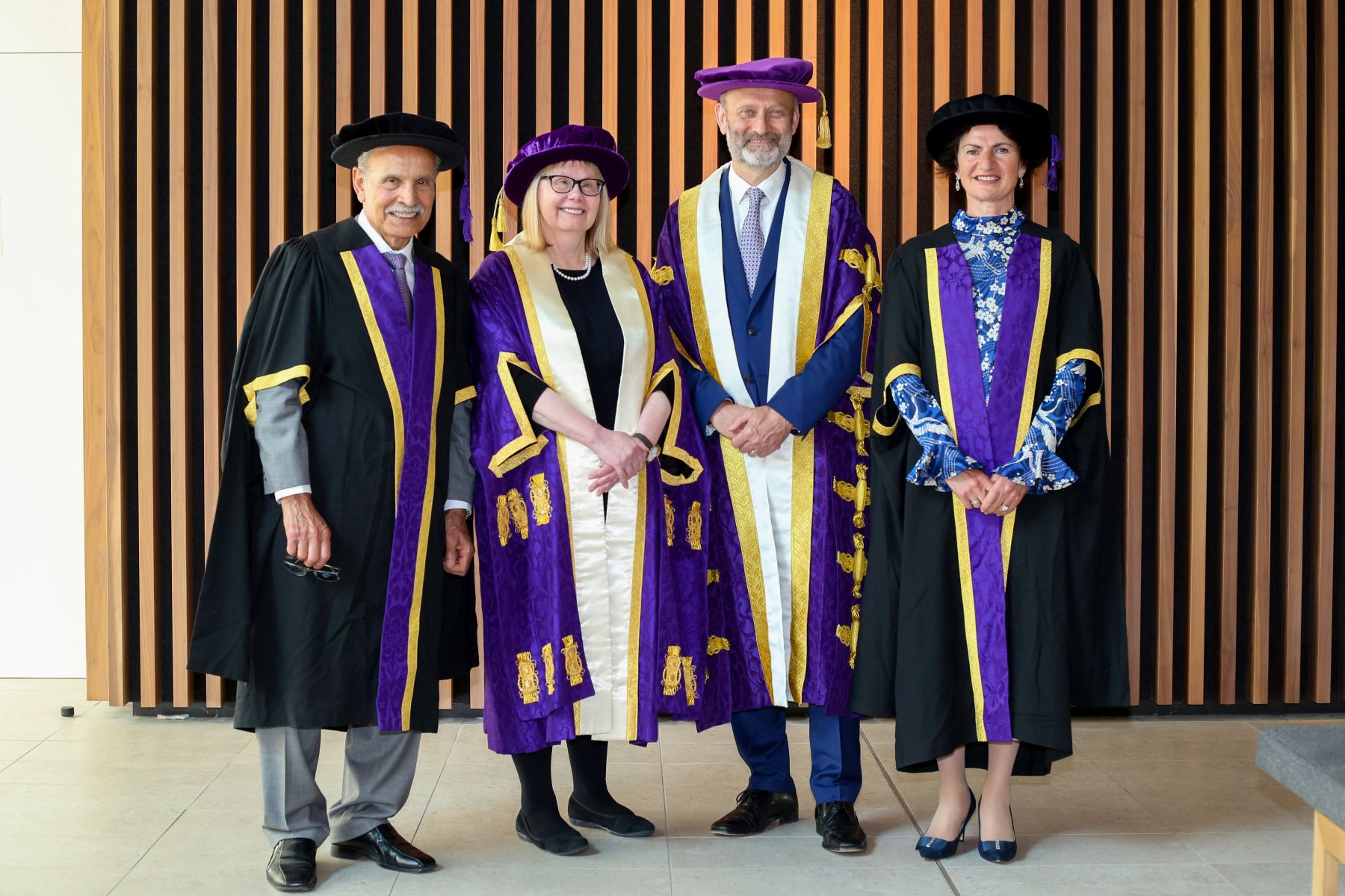 Four people in purple academic robes