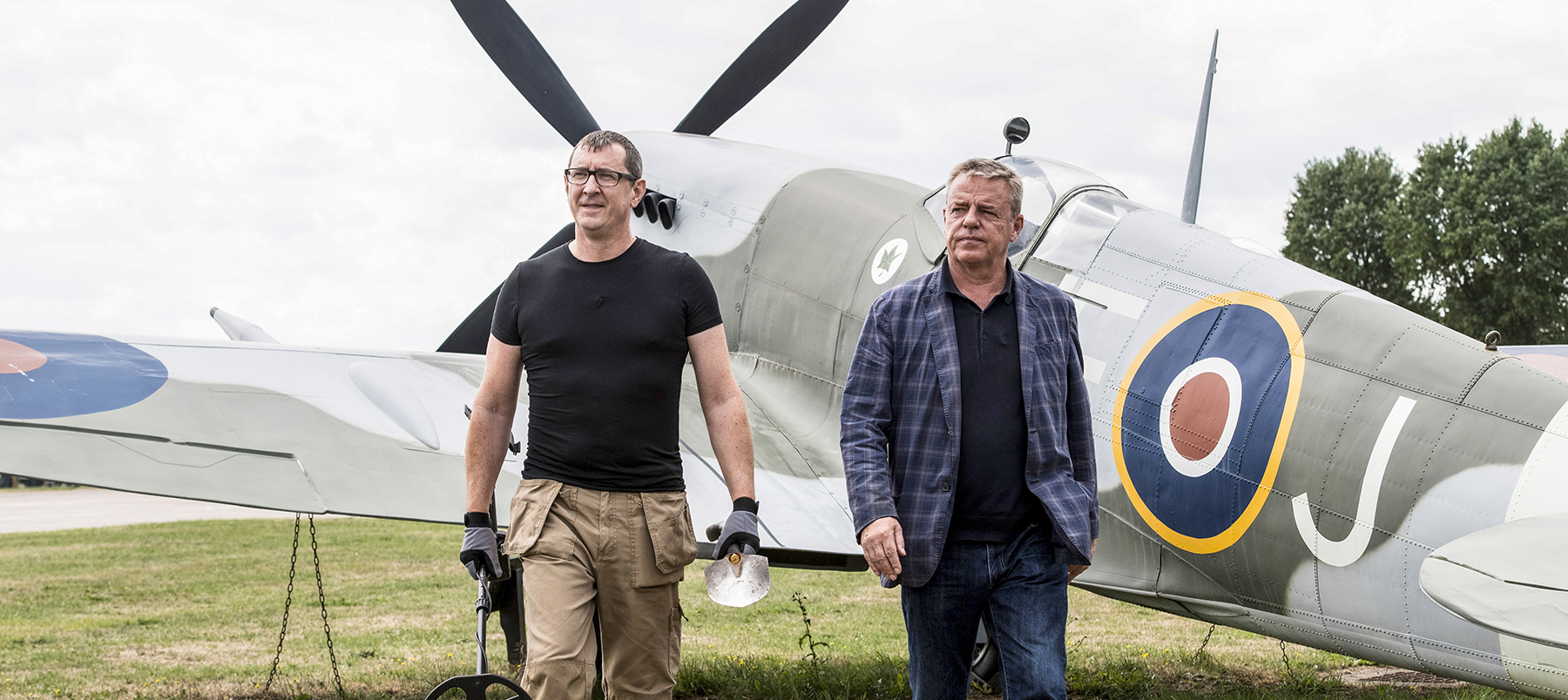 Two men standing beside a WW2 fighter plane