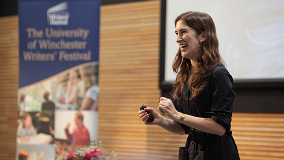 Young woman speaks to audience from a dais