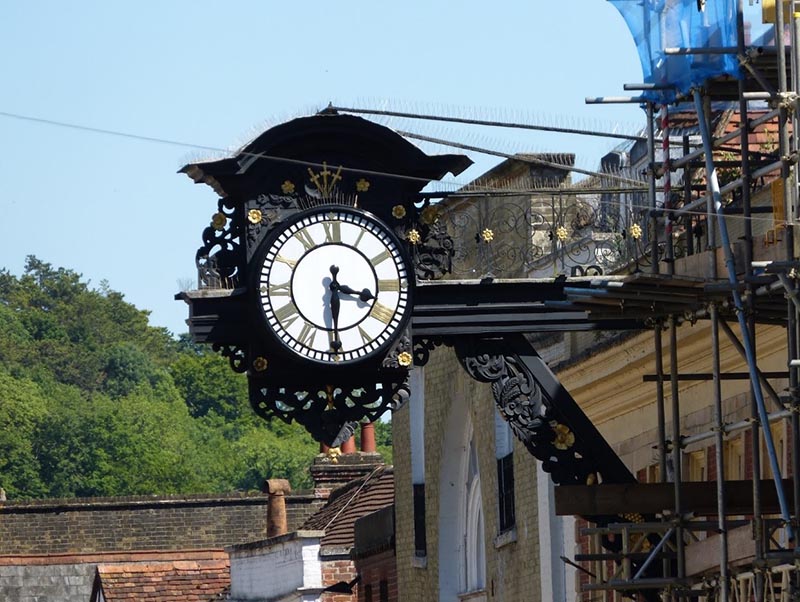 Ornate black clock on building in high street