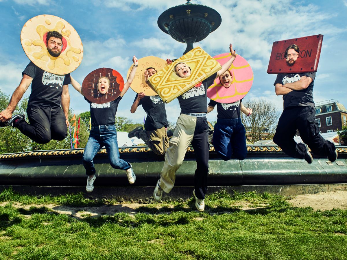 Five people with biscuit headdresses leaping in the air