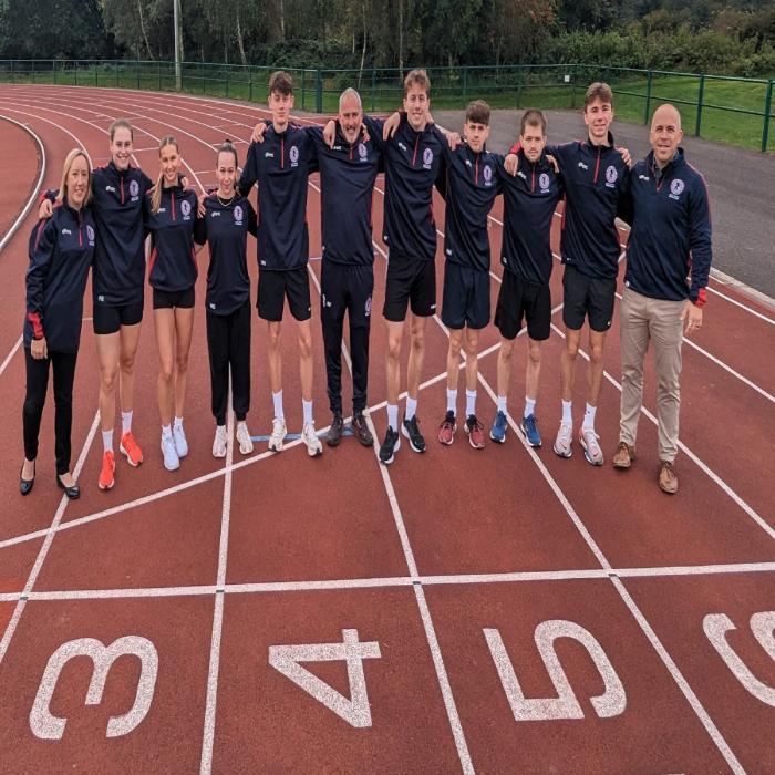 Young athletes and coaches on track standing shoulder to shoulder