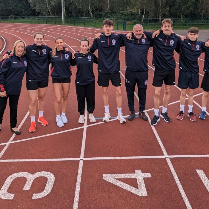 Young athletes and coaches on track standing shoulder to shoulder