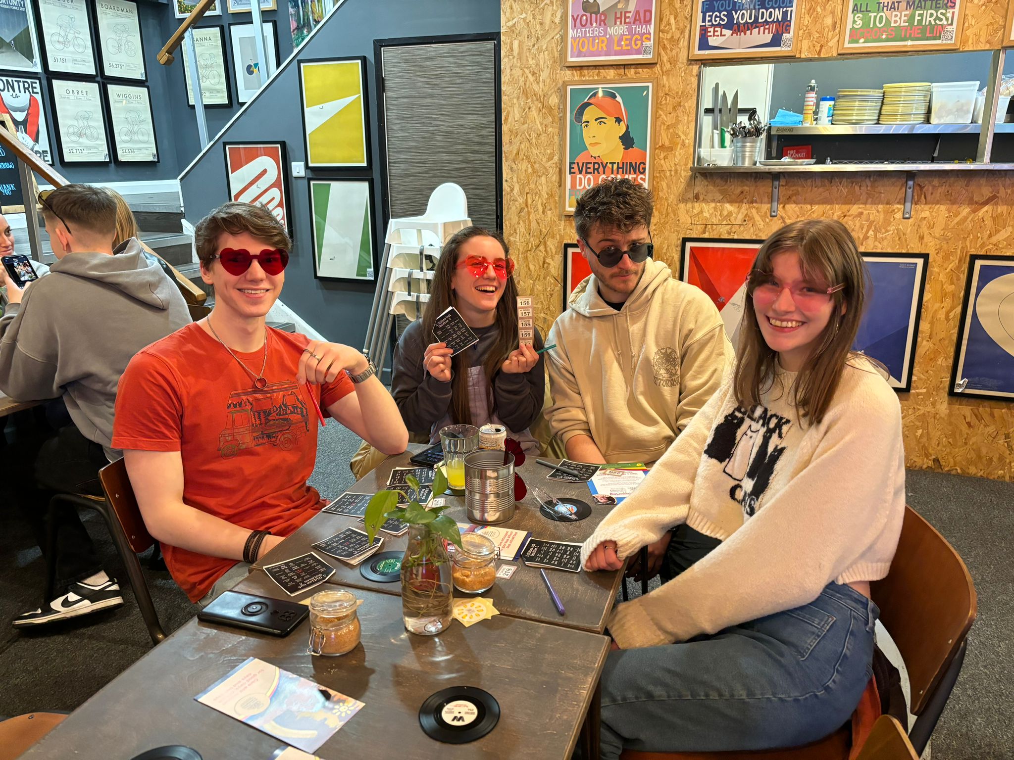 Four young people, two male two female, sat at table playing bingo