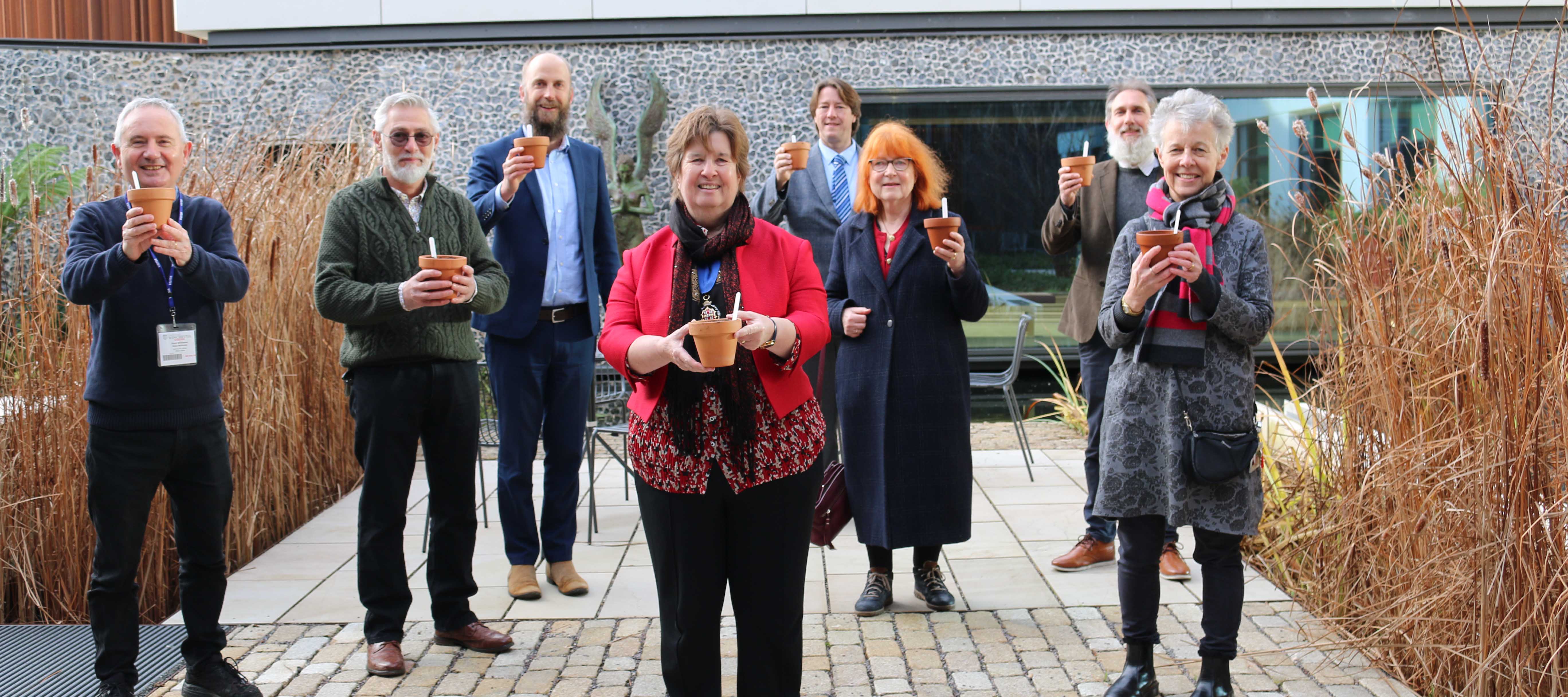 Group of people each holding a plant pot