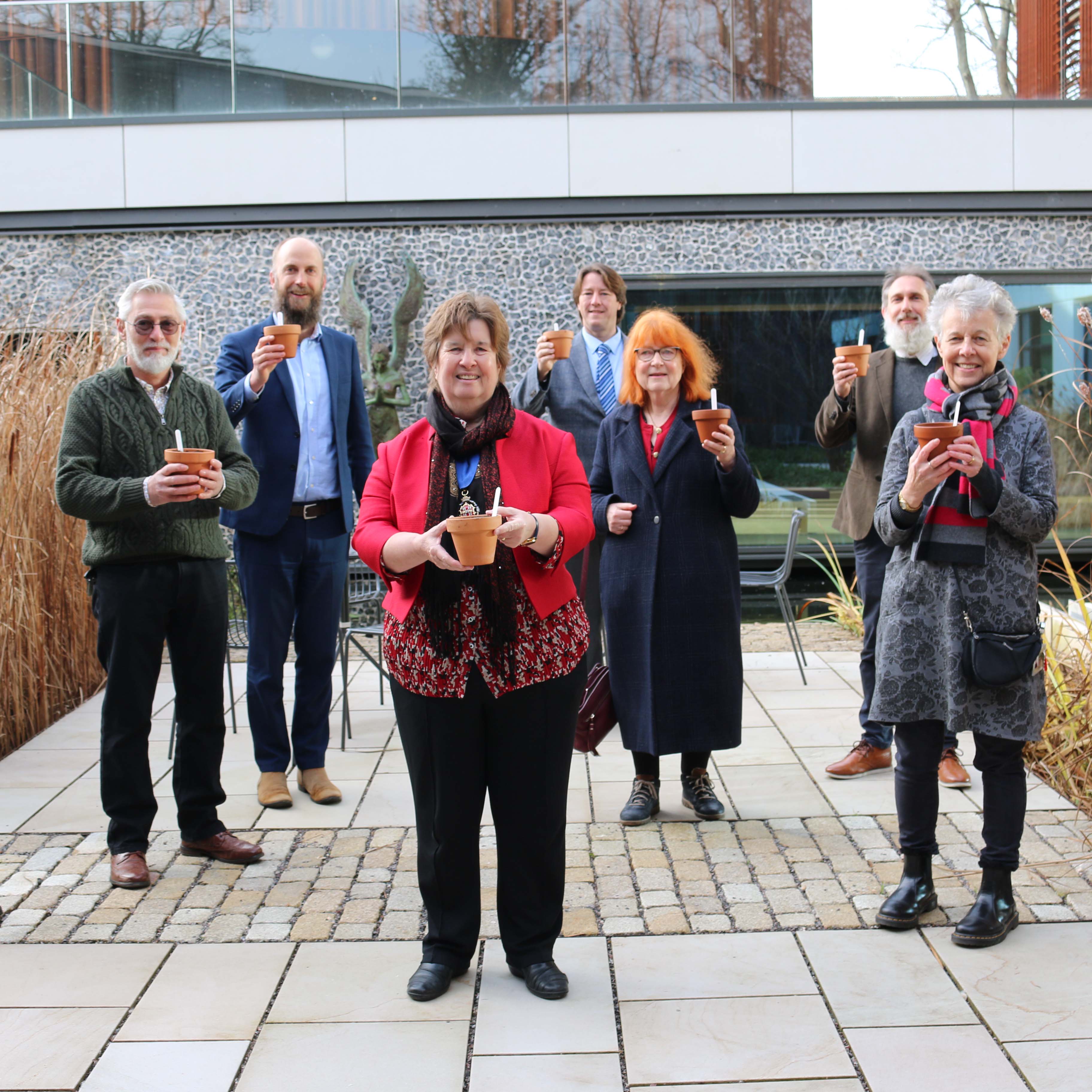 Group of people each holding a plant pot