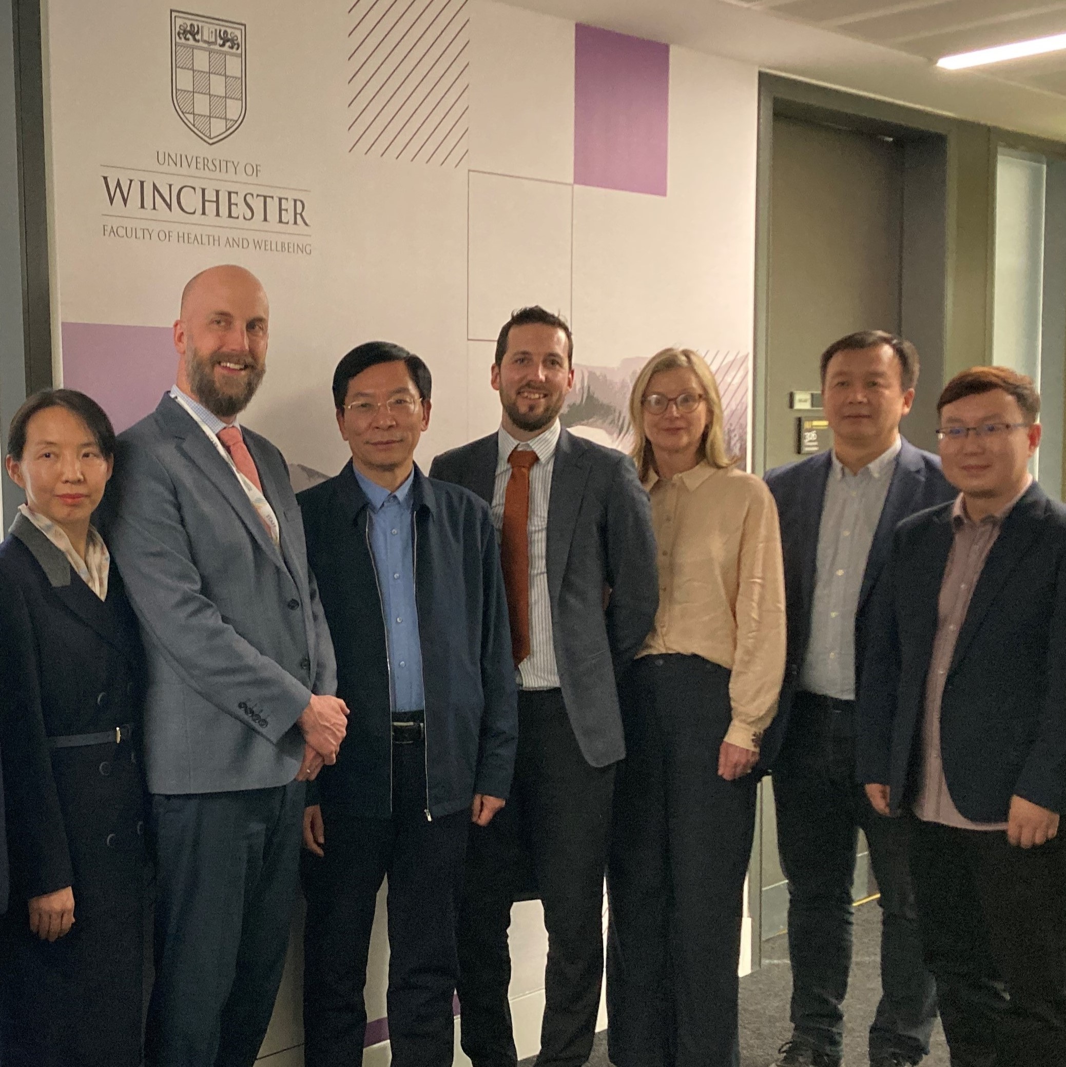 Group of people standing in front of University of Winchester signage