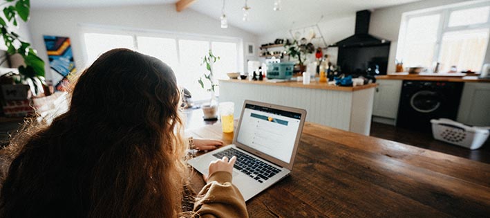 Girl sitting at kitchen table in front of a computer