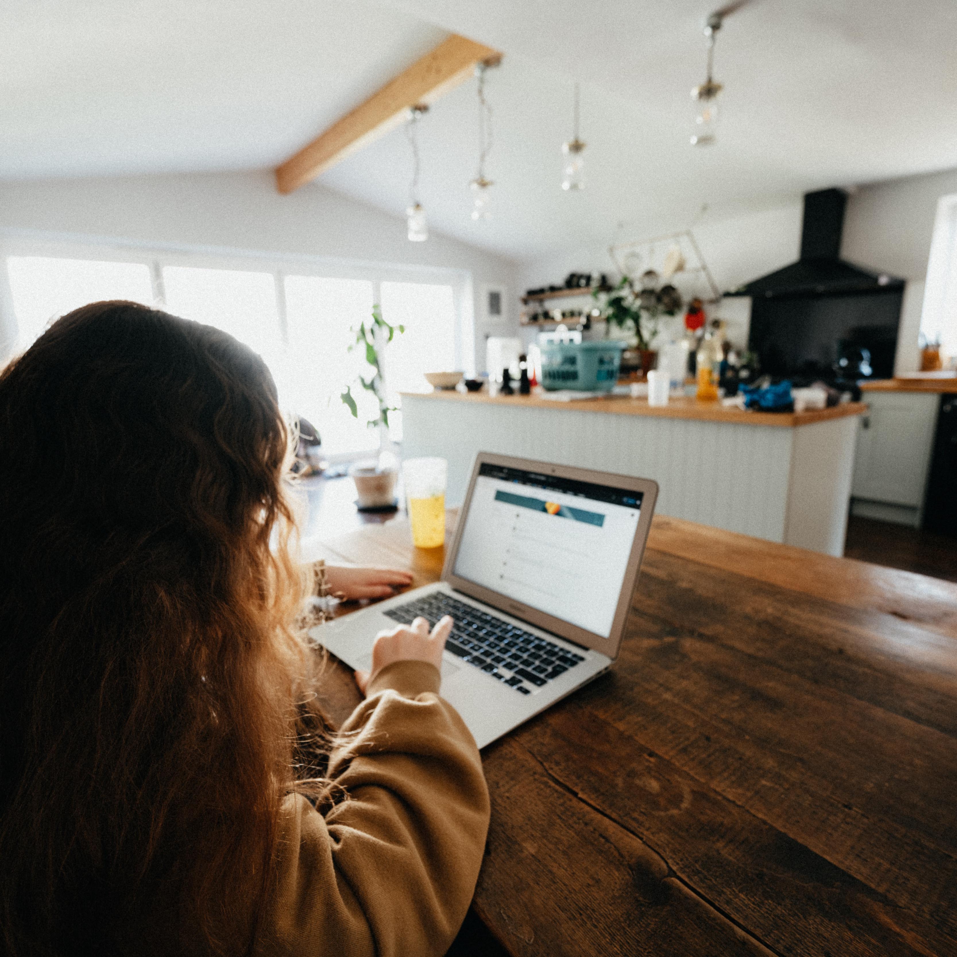 Girl sitting at kitchen table in front of a computer