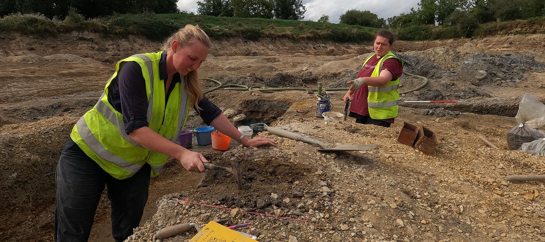 Archaeologists with tools digging a trench