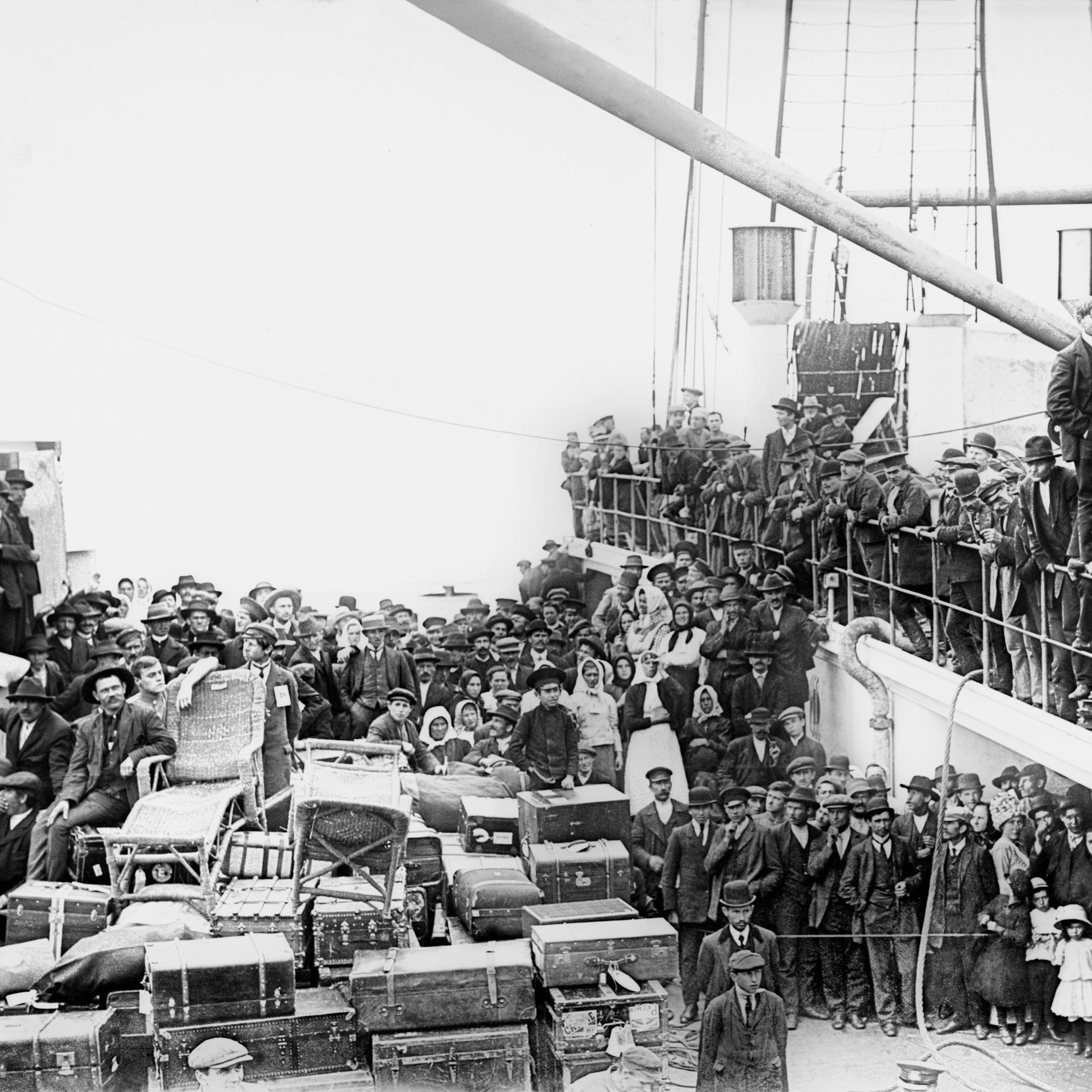 Black and white image of hundreds of immigrants packed onto deck of ship
