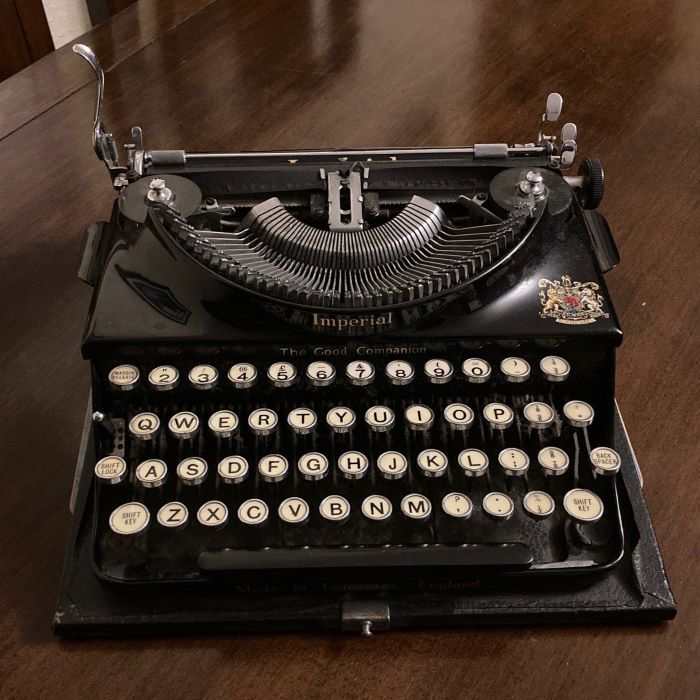 Woman and a man at typewriters facing each other across a desk