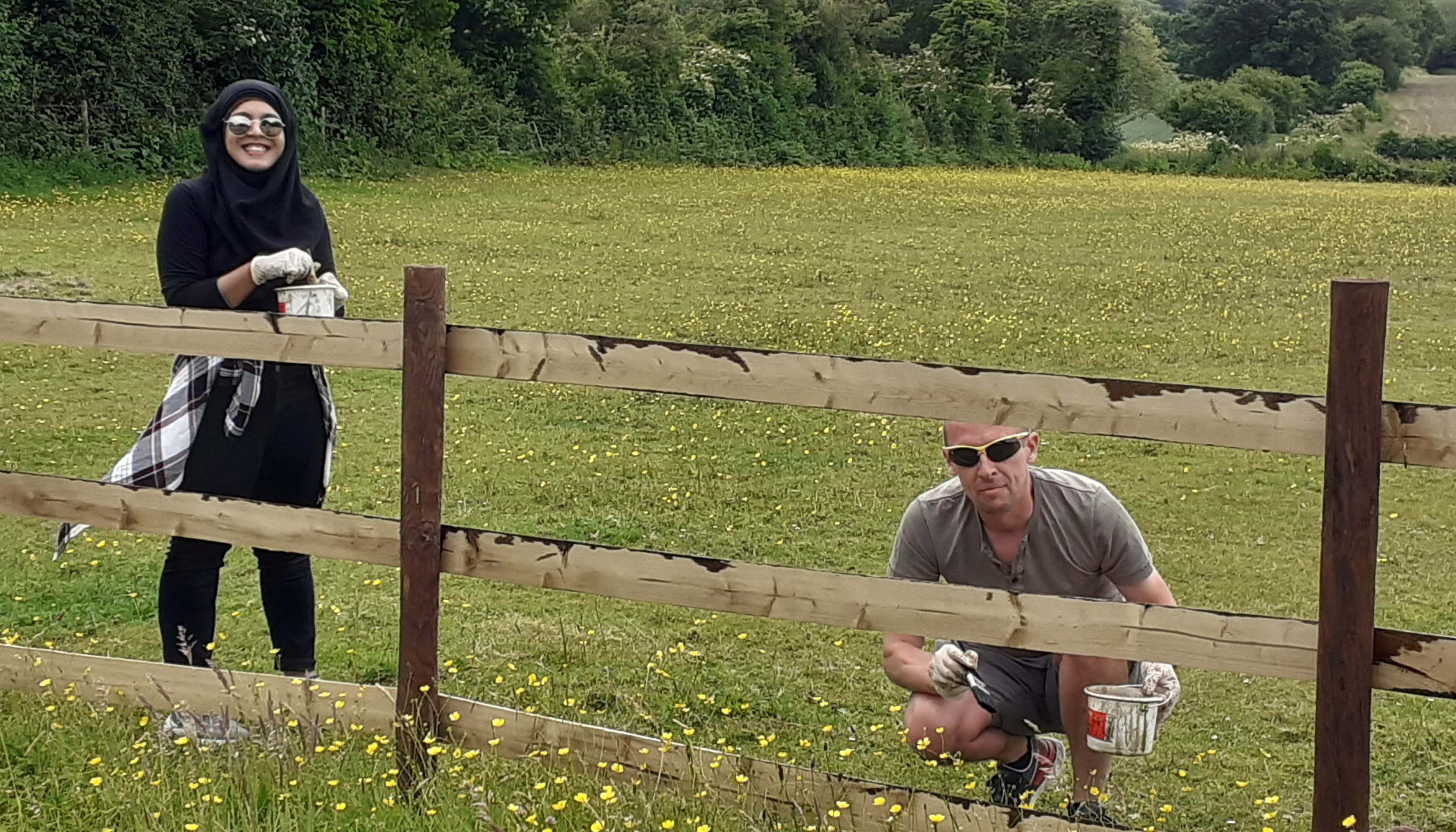 Two volunteers painting a fence