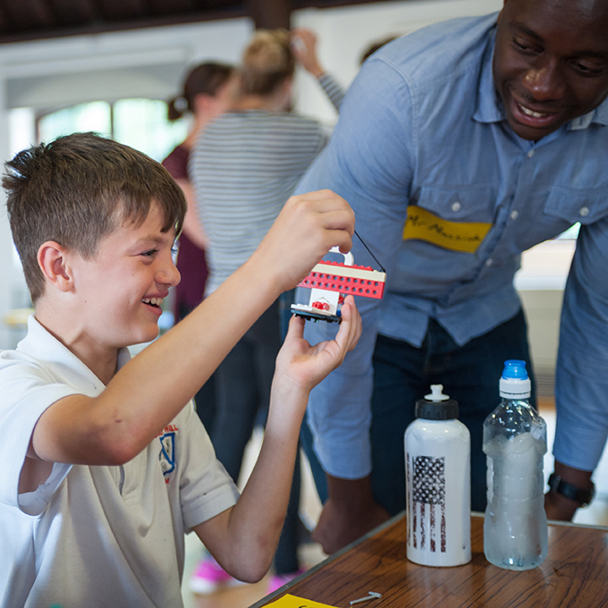 Child smiling while building Lego sculpture at school