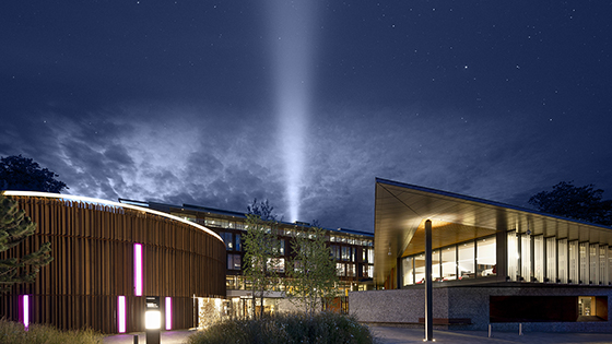 View of the front of the West Downs Centre with the beacon of hope beaming up into a dark night sky
