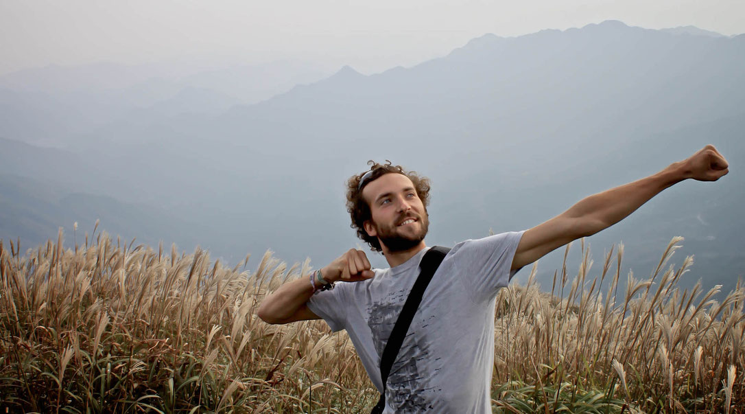 Stephen Cook posing in field with arms raised