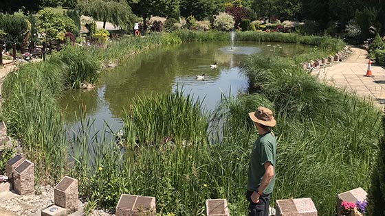 Man in hat standing next to large pond
