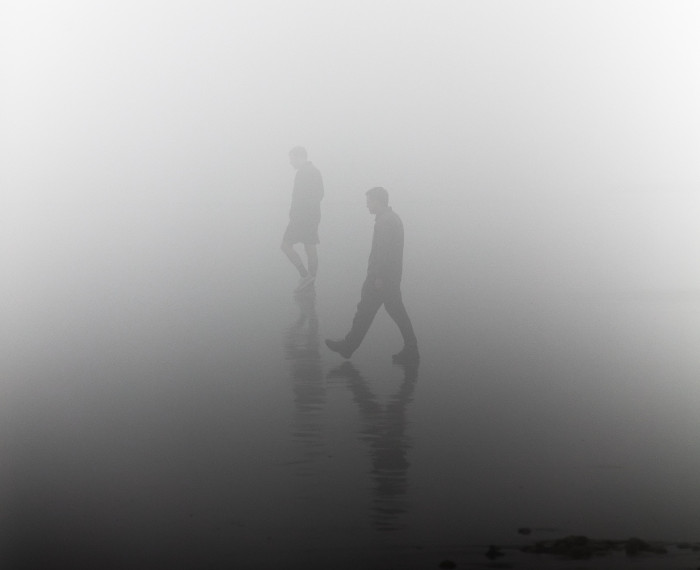 Two figures walking through fog