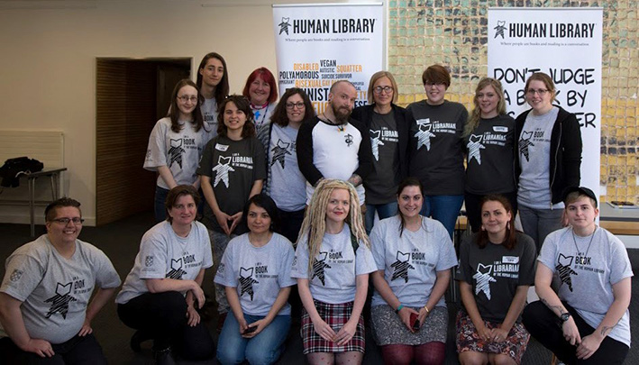 People representing human library 'books' and librarians are gathered in front of the Human Library display