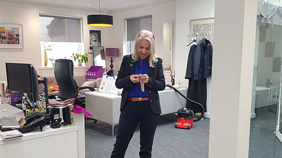 joy carter standing in her office opening a small gift