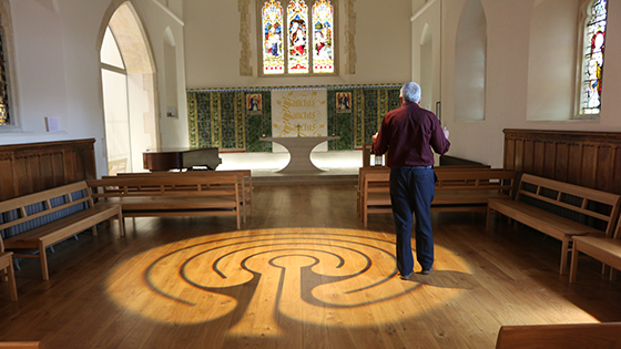 Light projection of a Labyrinth, a continuous line that weaves back on itself, on wooden floor of University of Winchester Chapel