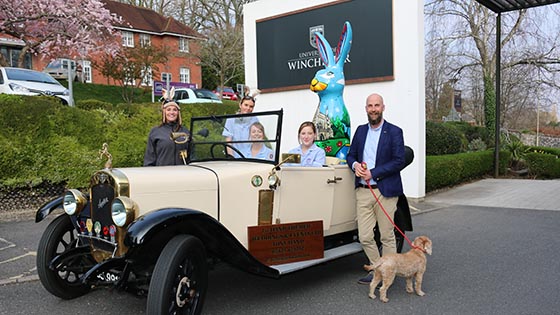 Giant hare sculpture in back of vintage open top car with student nurses