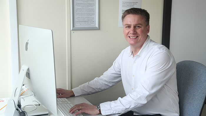 Man in white shirt sitting at desk with computer