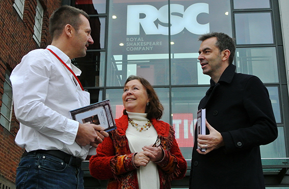 Millie Taylor pictured between two men outside the Royal Shakespeare Company building