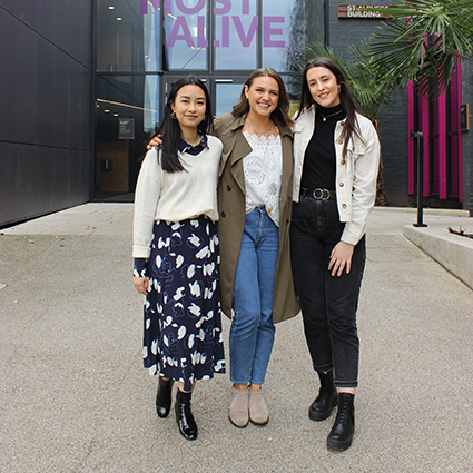 Fashion and lifestyle influencer Monica Welburn stands outside smiling with two Winchester students