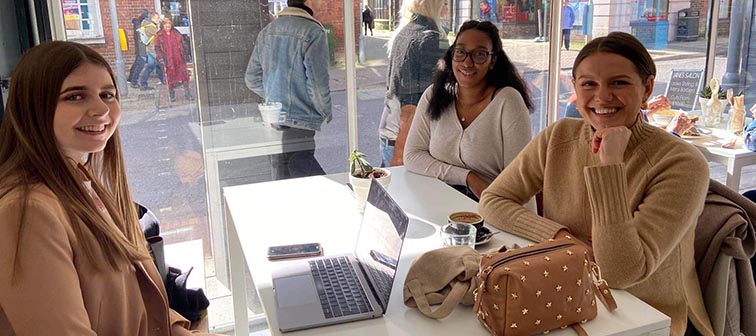 Rebecca Coleman and Caris sat at table smiling with Monica Welburn