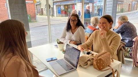 Rebecca Coleman and Caris sat at table smiling with Monica Welburn