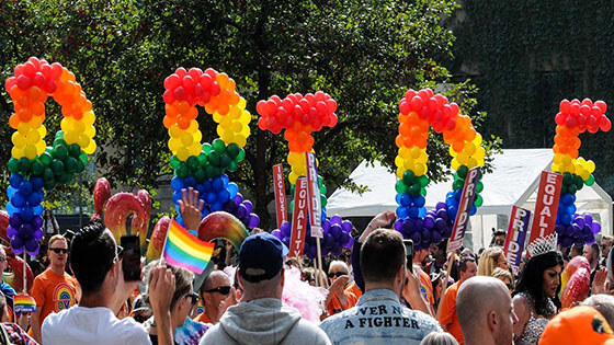 The letters for 'Pride' spelt out in rainbow balloons, held by pride supporters