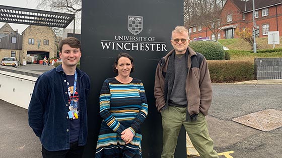 Three people standing by the entrance to the University