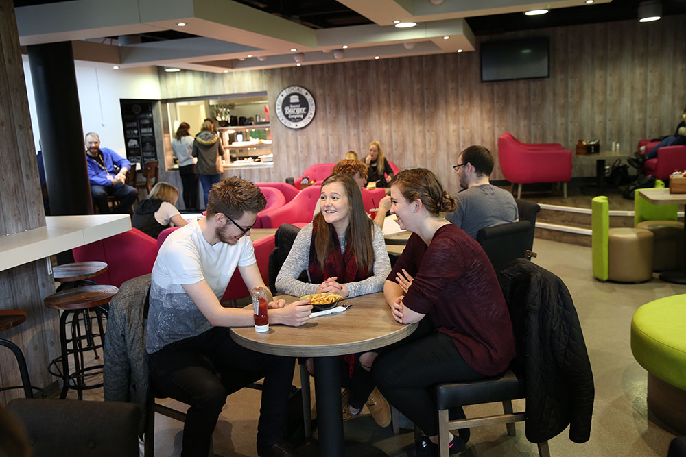Students sat around a table eating chips in The Lounge at University of Winchester