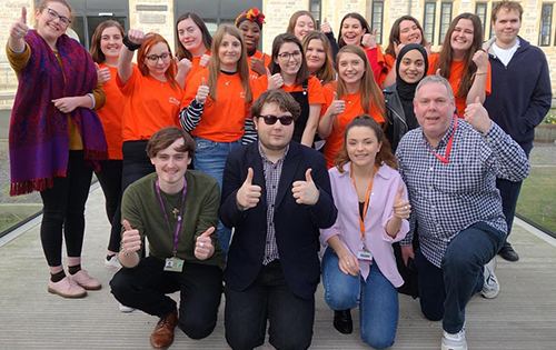 Student Volunteers in orange tops giving thumbs up