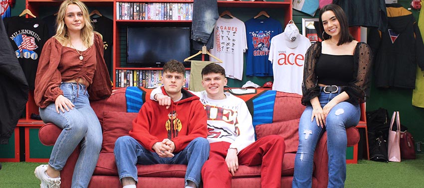 Students Natasha Coe and Caitlyn Raymond with the Edwards brothers of 1999 Vintage, seated on red sofa