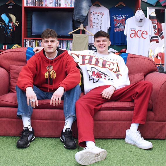 Students Natasha Coe and Caitlyn Raymond with the Edwards brothers of 1999 Vintage, seated on red sofa