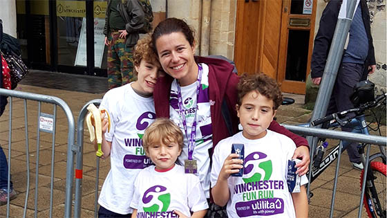 Dr Sarah Bayless wearing race medal, hugging three children