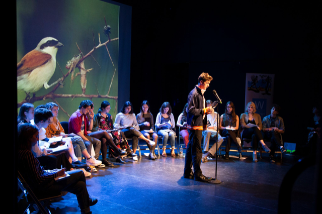 Teen boy at microphone with image of bird projected behind